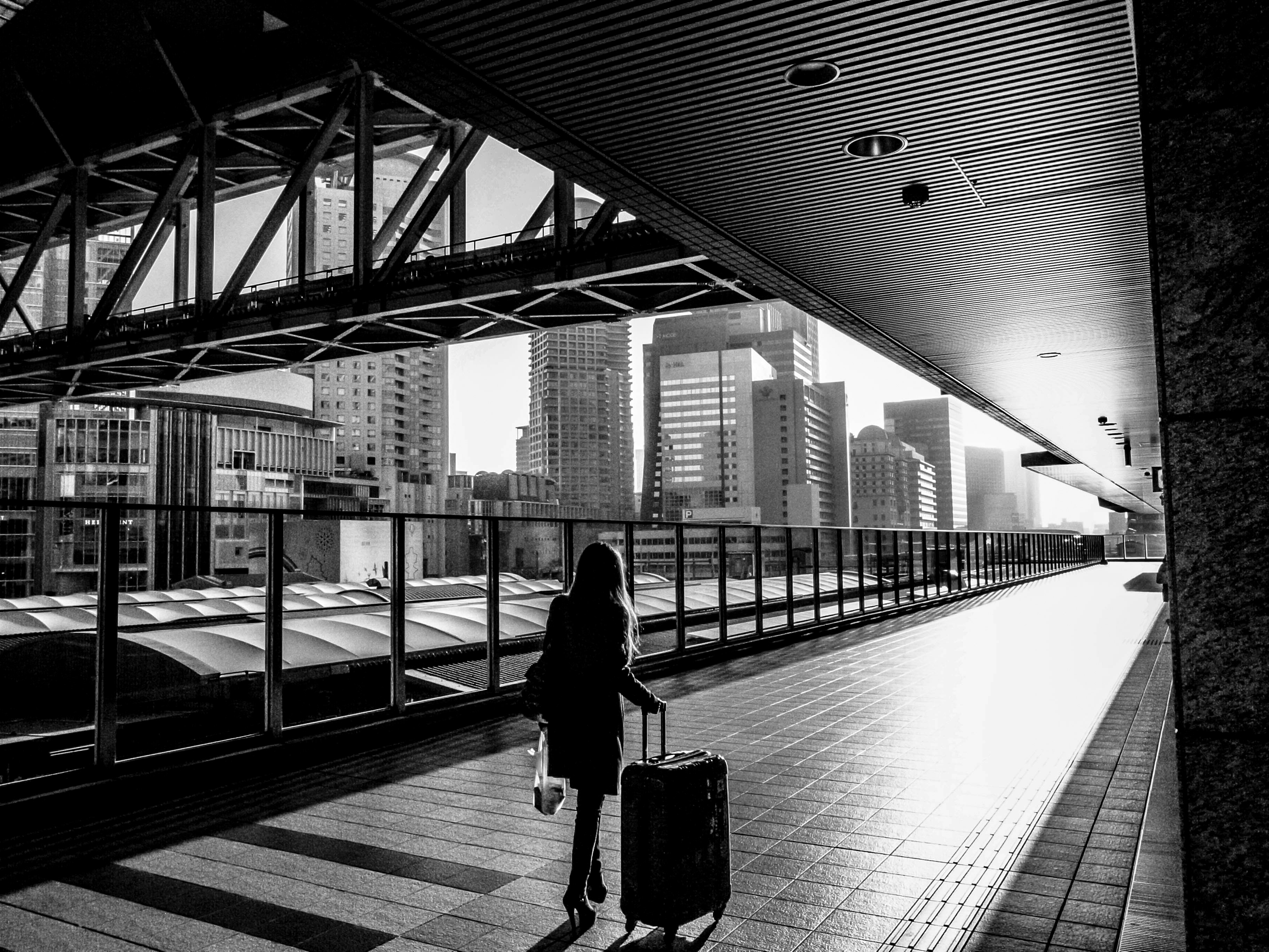 man in black jacket and pants walking on sidewalk during daytime